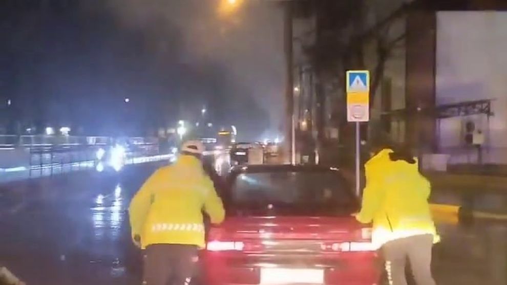 Arızalanan otomobili trafik polisleri yağmurun altında itti